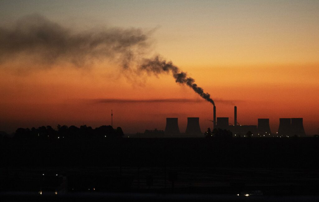 Power station emitting smoke at sunset, representing Eskom's load reduction measures to prevent transformer overloads during winter.