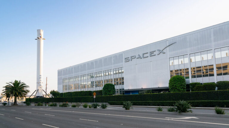 Exterior view of SpaceX headquarters in Hawthorne, California, showcasing the company's building and a rocket display.