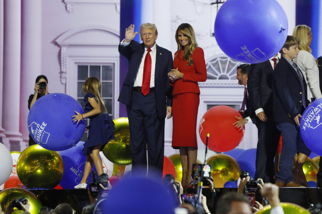 Donald Trump, with a bandage on his right ear, stands on stage with his wife Melania Trump and family, waving to the crowd after delivering his acceptance speech at the Republican National Convention in Milwaukee.