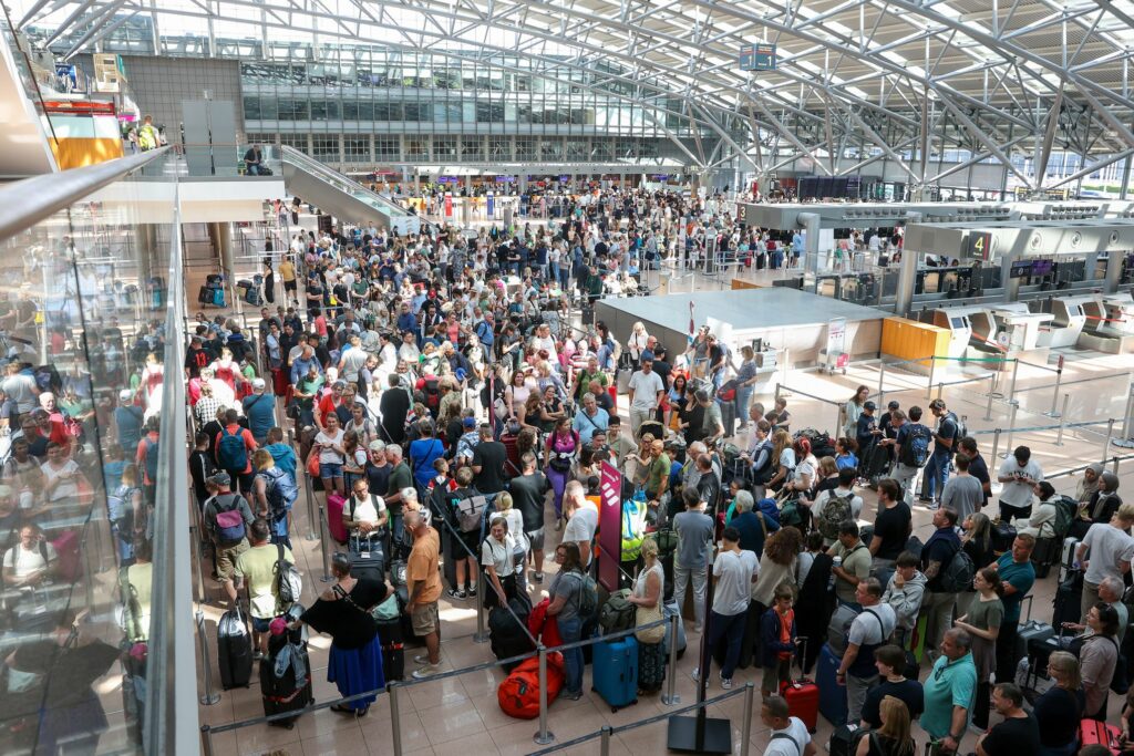 Crowded airport terminal with passengers affected by a global tech outage.