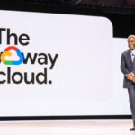 Thomas kurian ceo of google cloud standing on stage in front of a large screen displaying the phrase the new way to cloud during a company presentation