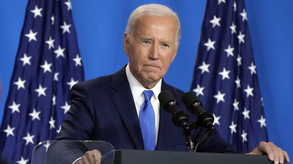 President joe biden speaking at a podium with american flags in the background