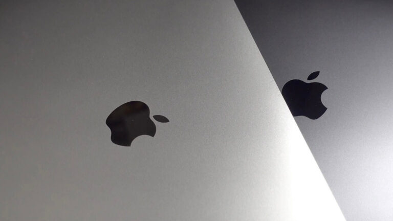 Close-up of Apple logos on silver and space gray Apple devices, highlighting the brand's iconic design.