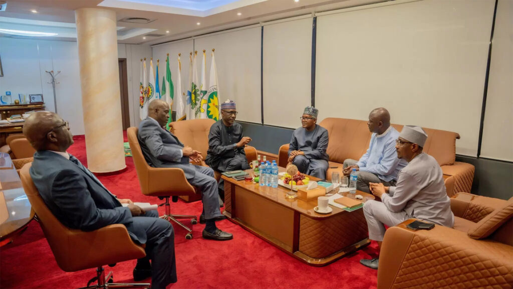 Aliko dangote and senior government officials seated around a table during a meeting to resolve a dispute with the nmdpra