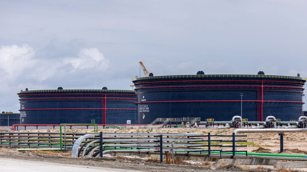 Large oil storage tanks at the dangote refinery in nigeria with a crane and pipelines visible