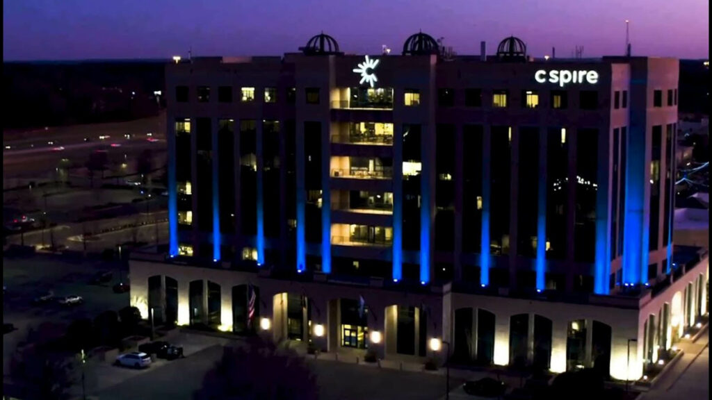 Night view of the C Spire headquarters building with blue and white lighting, highlighting its modern architecture.