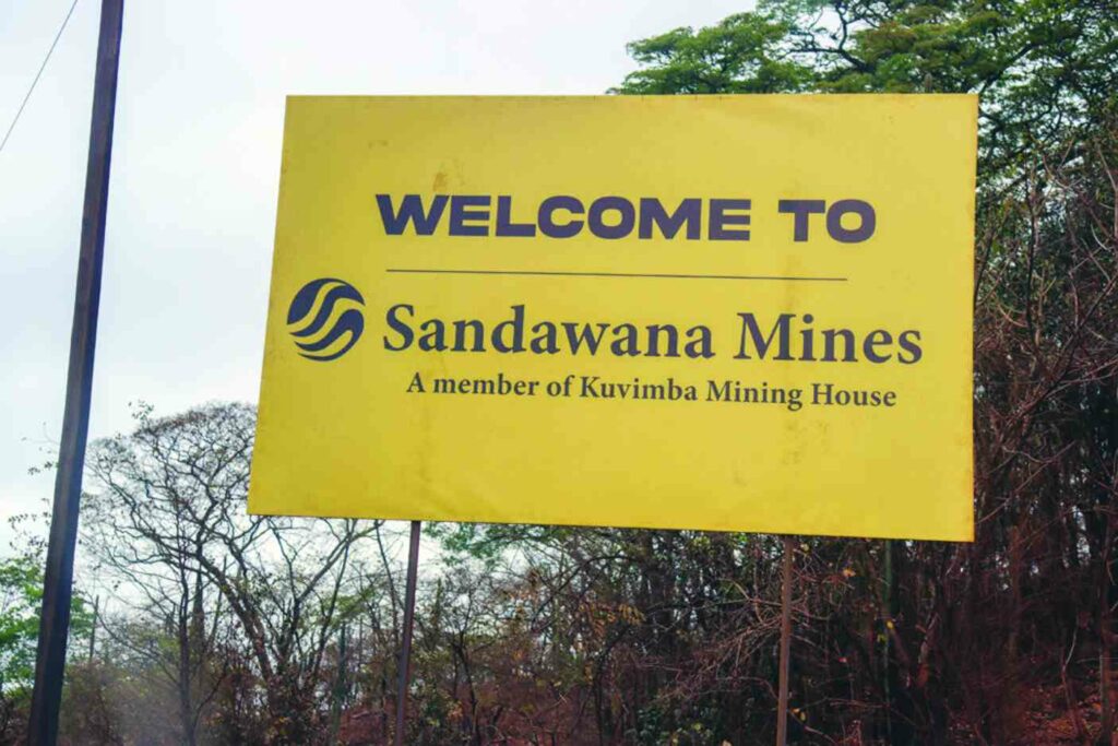 Welcome sign for Sandawana Mines, a member of Kuvimba Mining House, surrounded by greenery.