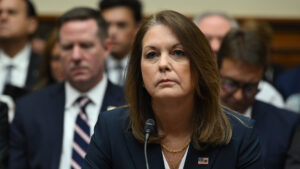 Kimberly cheatle chief of the u S Secret service speaking at a congressional hearing wearing a navy suit and gold necklace