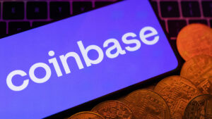 Coinbase logo on a screen, with cryptocurrency coins displayed below.