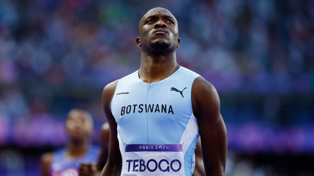 Tebogo Letsile standing proudly in his Botswana uniform after winning the 200-meter final at the Paris 2024 Olympics.