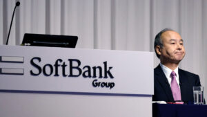 SoftBank CEO Masayoshi Son at a press conference, with a SoftBank Group logo on the podium.