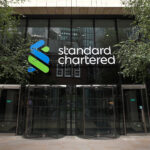 Entrance of standard chartered bank headquarters with the companys logo on the building facade