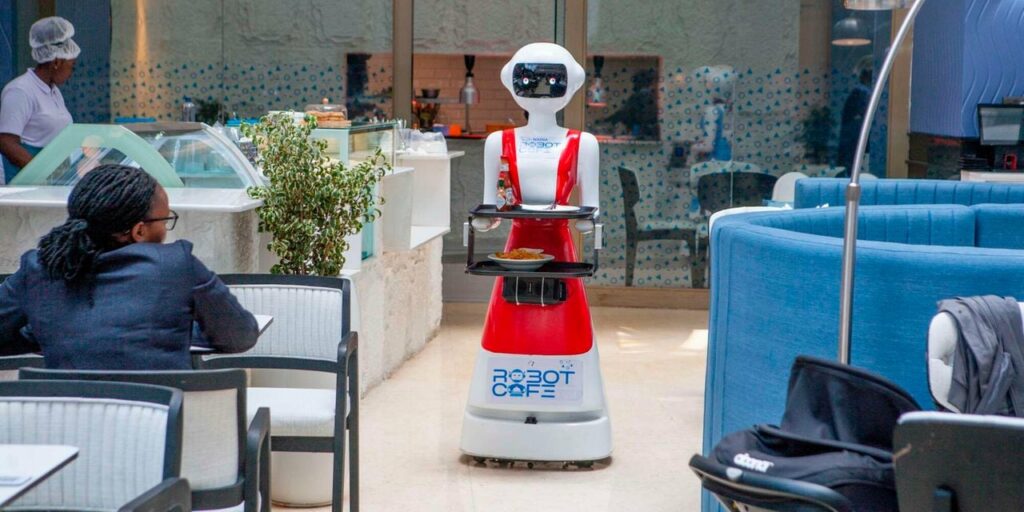 A robot waiter delivering food to a customer at Robot Café, highlighting the use of robotics in modern hospitality.