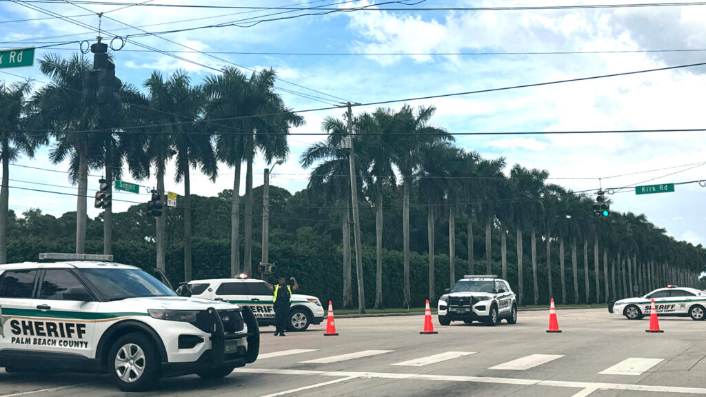 Palm beach county sheriffs vehicles block a road intersection with orange cones and officers direct traffic at kirk road and summit blvd