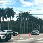 Palm Beach County Sheriff's vehicles block a road intersection with orange cones, and officers direct traffic at Kirk Road and Summit Blvd.