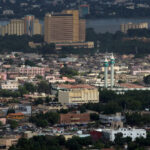 Aerial view of Bamako, Mali, with a mix of modern and traditional buildings, the Niger River, and notable landmarks.