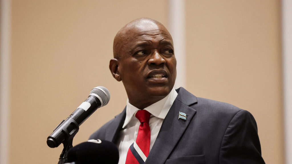 President mokgweetsi masisi wearing a suit and red striped tie speaks into a microphone looking to the side with a serious expression during his concession speech