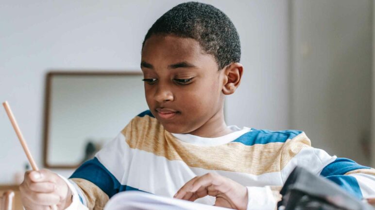 Student (boy) in a writing in a book