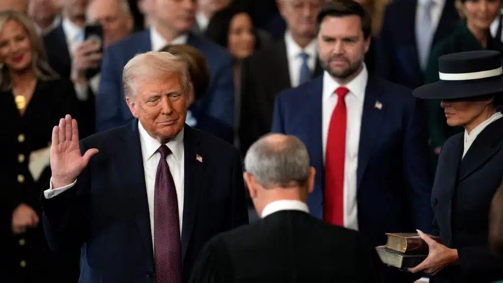 Donald trump raises his hand during the oath of office as the 47th president of the united states with chief justice john roberts presiding and melania trump holding the bible