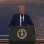 President donald trump delivers a speech at the presidential podium standing in front of a backdrop featuring the u S Presidential seal and an e pluribus unum emblem