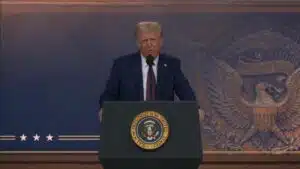 President donald trump delivers a speech at the presidential podium standing in front of a backdrop featuring the u S Presidential seal and an e pluribus unum emblem