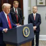 President Donald Trump speaks at the podium during the launch of Project Stargate, flanked by industry leaders in a ceremony emphasizing the transformative AI infrastructure initiative.