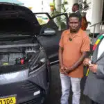 Zimbabwean President Emmerson Mnangagwa and inventor Maxwell Chikumbutso stand beside a self-powering vehicle with an open hood at State House in Harare, discussing groundbreaking technology.