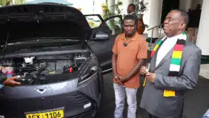 Zimbabwean president emmerson mnangagwa and inventor maxwell chikumbutso stand beside a self powering vehicle with an open hood at state house in harare discussing groundbreaking technology