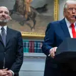 Former U.S. President Donald Trump speaks at a podium in the White House, with U.S. Senate Commerce Secretary Howard Lutnick standing beside him.