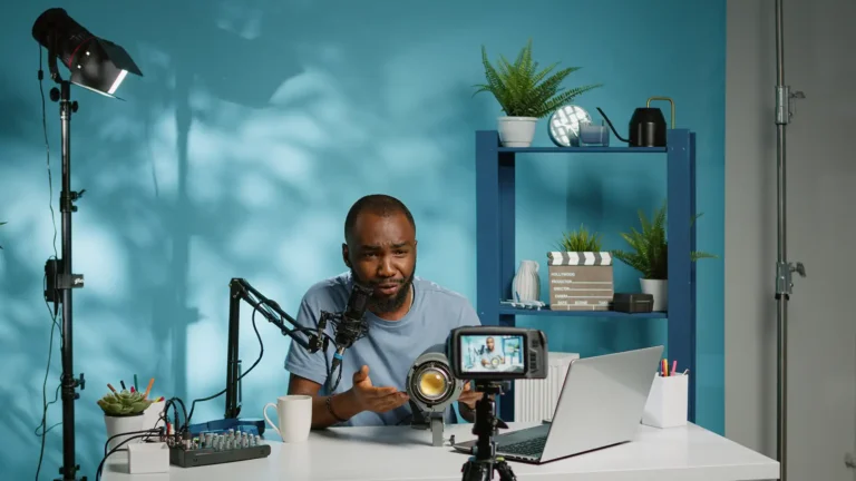 Black content creator recording a video tutorial with camera, microphone, lighting setup, and a laptop in a creative studio.