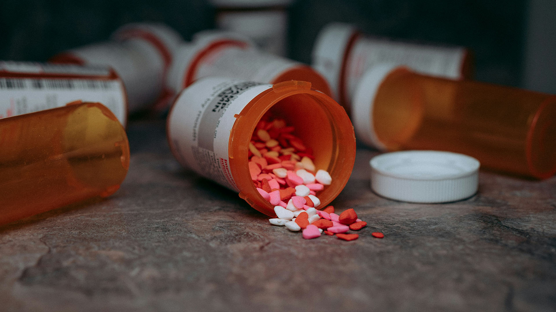 Prescription pill bottle spilling colorful heart-shaped tablets