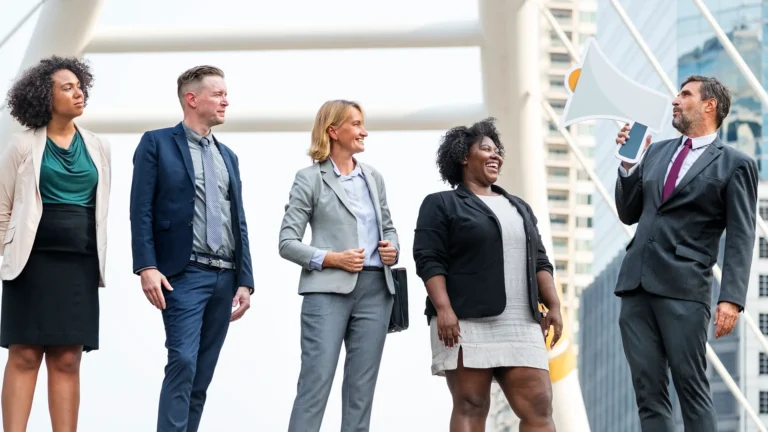 Group of business leaders standing outdoors, one speaking through a megaphone