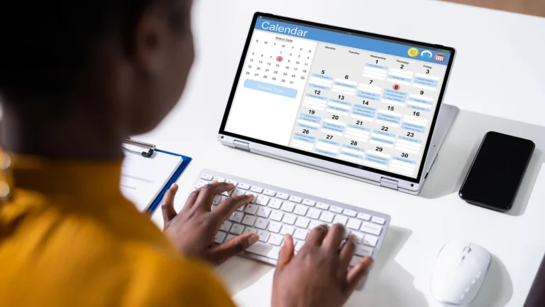 A person using an online calendar app to plan and schedule tasks on a laptop.