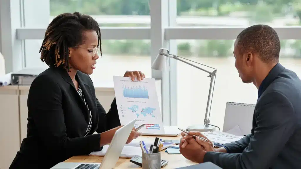Businesswoman presenting analytics charts to a colleague during a meeting.