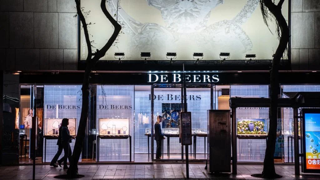 De Beers Luxury Flagship Storefront at Night | Brimco Nighttime exterior of a de beers jewelry store with lit window displays and pedestrians walking past