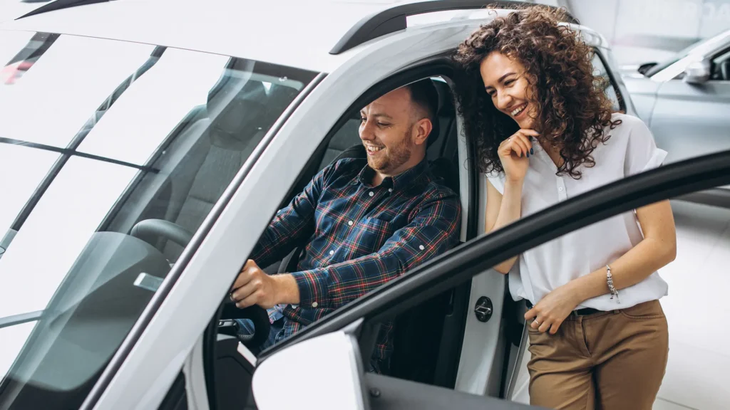 Insurance broker leaning into the car with the client