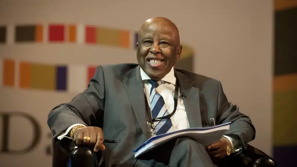 Former Botswana President Festus Mogae at Public Forum | Brimco Former botswana president festus mogae seated in a chair smiling while holding documents during a public event